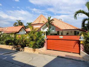 ein Haus mit einem großen orangefarbenen Tor davor in der Unterkunft CORNER VILLA - PATTAYA HOLIDAY HOUSE WALKING STREET 4 bedrooms in Pattaya South
