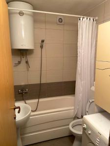 een badkamer met een bad, een toilet en een wastafel bij Prishtina Center Apartment in Pristina