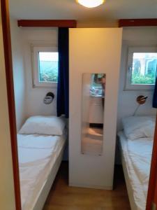 duas camas num pequeno quarto com duas janelas em Chalet de Putter in Putten em Krachtighuizen