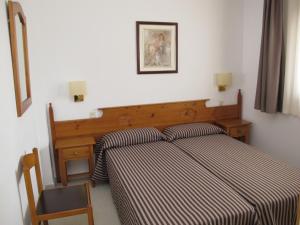 a bedroom with a bed with a striped bedspread and a desk at Apartamentos Santi in Lloret de Mar