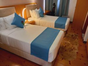 Z Addis Hotel في أديس أبابا: غرفة فندقية بسريرين ذات شراشف زرقاء وبيضاء