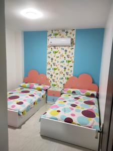 two beds in a room with blue walls at شالية مميز بقرية مارينا دلتا السياحية ol2o72ool82 in ‘Izbat Abū Sulayman
