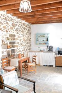a dining room with a table and a stone wall at Volcano View Nisyros in Emporeiós