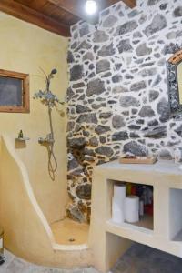 a bathroom with a stone wall with a shower at Volcano View Nisyros in Emporeiós