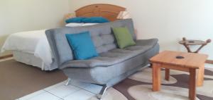 uma sala de estar com um sofá e uma cama em Liz' Cottage em Mbabane
