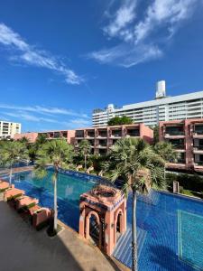 Una piscina con palmeras y un edificio. en Baan Marakesh Hua Hin, en Hua Hin