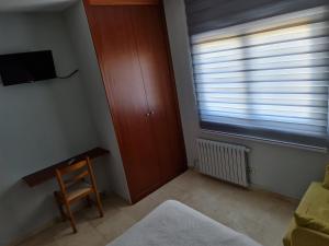 um quarto com uma janela, uma cadeira e uma secretária em Hospedaxe Don Manuel em Vicedo