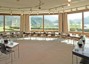 a large room with tables and chairs and large windows at Landzeit Motor-Hotel Mondsee in Mondsee