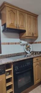 a kitchen with a black oven and wooden cabinets at CASA DE LOS ABUELOS in Ortigosa del Monte