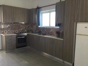 cocina con armarios de madera, fregadero y ventana en Artemis Apartments, en Almyrida