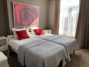 two beds in a hotel room with red pillows at Hotel Hooghuys in Hamont +10 photos