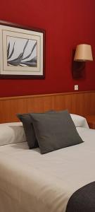 a bed in a bedroom with a red wall at Hostal Regina in Blanes