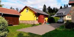 uma casa amarela e vermelha com um carro estacionado numa garagem em Ferienhaus Brigitte em Klingenthal