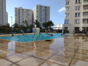 - une piscine avec des personnes qui y nagent avec de grands bâtiments dans l'établissement Departamento Coquimbo a pasos de la playa, à Coquimbo