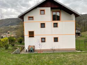 a white house with a table and chairs in a field at Porodicna kuca za odmor Kovaci in Zavidovići