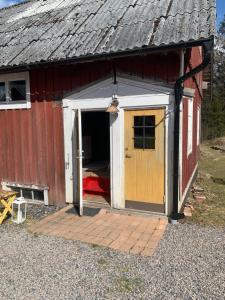un granero rojo y blanco con una puerta abierta en En lantlig idyll med skogen precis utanför dörren! en Ullared