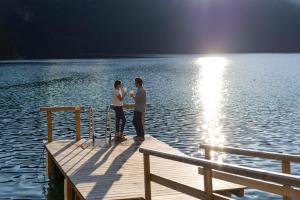 two people standing on a dock on a lake at Eibsee Hotel in Grainau