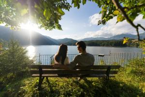 a man and woman sitting on a bench near a lake at Eibsee Hotel in Grainau