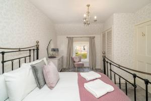 una camera da letto con un letto con lenzuola bianche e cuscini rosa di Thrums Cottage a Kirriemuir