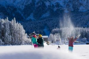 a group of people standing in the snow with a dog at Eibsee Hotel in Grainau