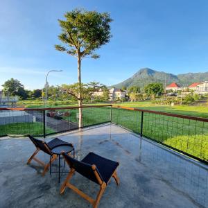 a patio with two chairs and a table and a tree at Casa Terra in Batu