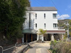 un edificio blanco con una entrada delante de él en 熱海温泉　実の別荘 en Atami