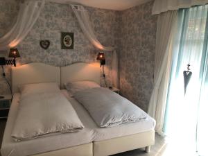 a white bed in a bedroom with a window at Romantikmühle Heartlandranch in Krummenau