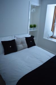 uma cama branca com almofadas pretas e uma janela em No.34 Apartment em Perth