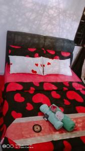 a bed with red flowers on it with two dolls on it at New Garden View GF Double Room FREE parking in Batu Unjor