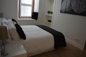 a bedroom with a bed with white sheets and black pillows at No.34 Apartment in Perth