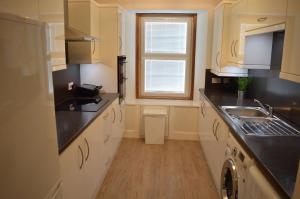 uma cozinha com armários brancos, um lavatório e uma janela em No.34 Apartment em Perth