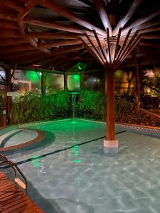 a swimming pool in a resort with a wooden ceiling at Pousada Kaloa Eco Village in Bombinhas