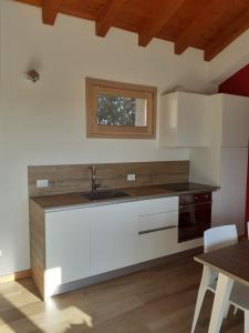 a kitchen with white cabinets and a sink and a table at Ex Cinquantadue in Pasiano di Pordenone