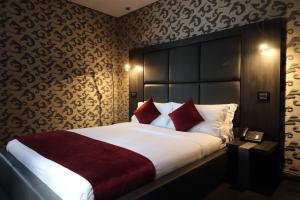 a bedroom with a large bed with red pillows at The Bryson Hotel in London