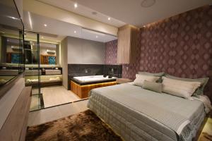 a bedroom with a large bed and a bath room at Pousada Chão de Folhas SPA Boutique in Águas de Lindoia