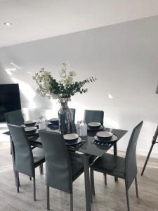 a black dining room table with chairs and a vase with flowers at The Barbican Penthouse in Plymouth