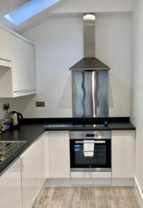 a kitchen with white cabinets and a stove top oven at The Barbican Penthouse in Plymouth