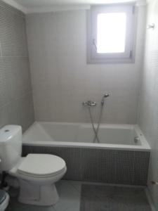 a bathroom with a toilet and a bath tub with a window at Villa TERVEL in Xanthi