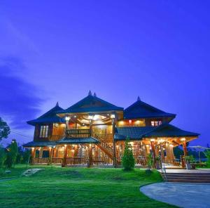 a large wooden building with lights on it at night at Baan Maneekan in Sukhothai