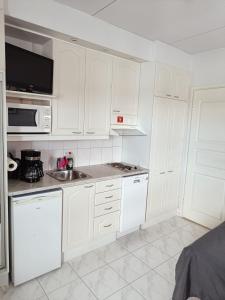 une cuisine blanche avec un évier et un micro-ondes dans l'établissement Saunallinen lomahuoneisto LeviStar 1, à Kittilä