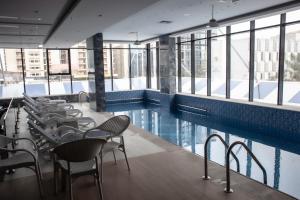 a swimming pool with chairs and tables and windows at Rio Hotel Olaya in Riyadh