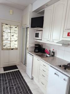 une cuisine blanche avec des armoires blanches et un évier dans l'établissement Saunallinen lomahuoneisto LeviStar 1, à Kittilä 1 autre photo