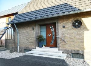 une maison en briques avec une porte marron et des escaliers. dans l'établissement Haus Hirt-Nettetal, à Nettetal