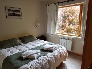 Un dormitorio con una cama con dos almohadas y una ventana. en Golondrinas - Andarlibre, en San Martín de los Andes 25 fotos más