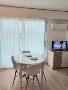 een witte tafel en stoelen in een woonkamer met een televisie bij STUDIO HYERES PORT in Hyères