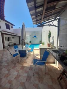 un patio con mesa, sillas y piscina en POUSADA BEIRUTE, en Cabo Frío