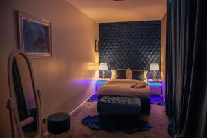 ein Schlafzimmer mit einem großen Bett mit blauem Licht in der Unterkunft Cosy Luxury Suite Jewellery Quarter - Birmingham in Birmingham