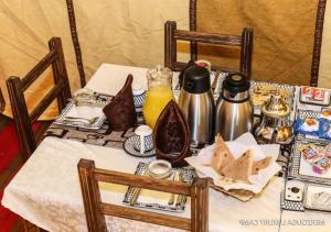 une table avec un tissu de table blanc et de la nourriture dans l'établissement Sahara Relax Camps, à Zagora