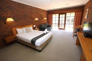 a bedroom with a bed and a brick wall at Grange Burn Motel in Hamilton