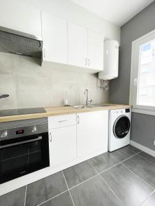 a kitchen with white cabinets and a dishwasher at Apartamento San Isidoro in Santiago de Compostela